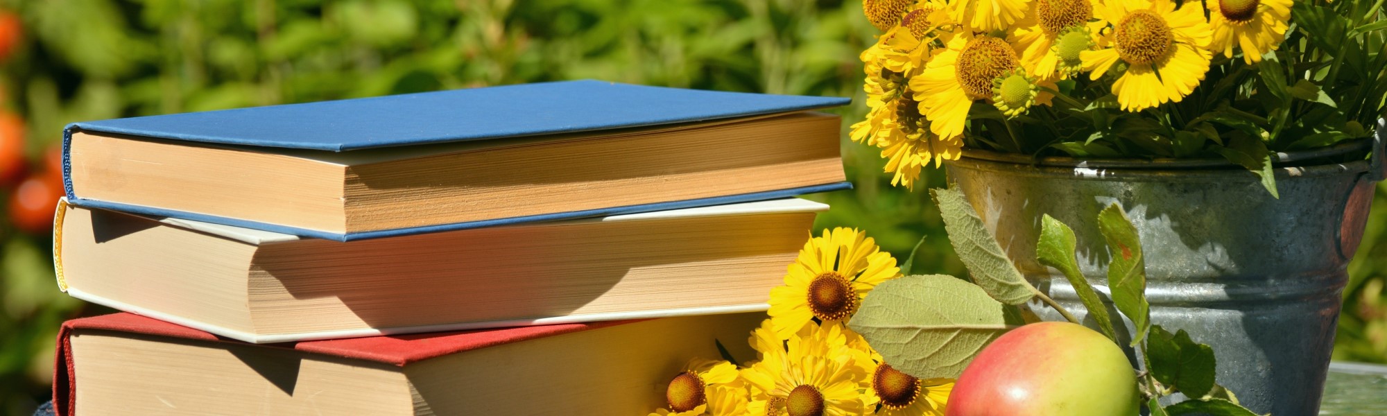 books in grass with flowers